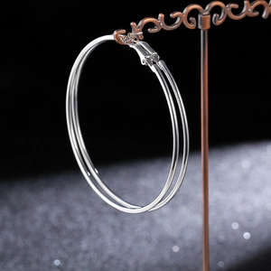 Macro side view of polished silver hoop earrings hanging on a vintage metal stand