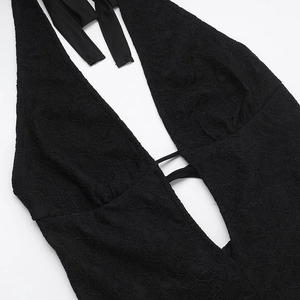 Close-up of intricate black lace texture and plunging V-neckline detail on chic jumpsuit