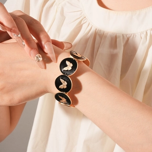 Detail of vintage gold bracelet featuring black enamel discs and embossed butterfly motifs