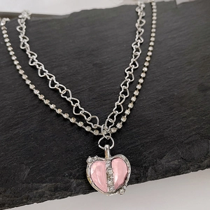Detail of double-layer necklace with pink heart pendant and rhinestone heart chain link