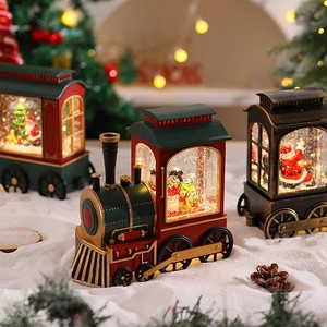 Close-up of three vintage Christmas train snow globes with glowing lights and falling snow