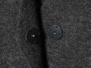 Gros plan sur la texture laineuse gris foncé et le bouton-pression en métal noir