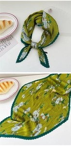 Detail of green pleated scarf with white floral butterfly print and wavy stitched edges