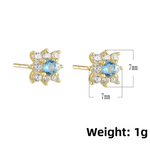 Macro detail of gold flower stud earrings with blue and white zircon stones 7mm size