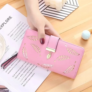 Detail of light pink leather wallet with leaf cutout patterns and a golden leaf pendant