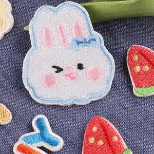 Embroidered cartoon white rabbit and strawberry patches on dark denim background