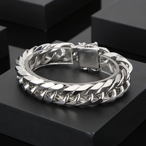 Silver 16mm thick Cuban link chain bracelet with square buckle on black jewelry boxes