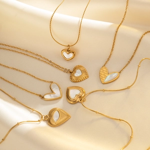 Detailed view of six 18k gold plated heart pendants with mother of pearl on silk background