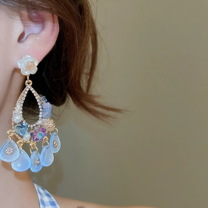 Detail of luxury flower drop earrings with crystals and light blue resin tassels