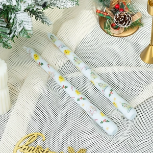 Détail de bougies de Noël avec impressions festives sur tissu blanc texturé