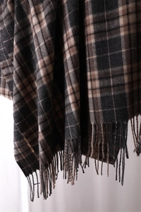 Close-up of soft cashmere-feel scarf with brown and black plaid pattern and tassel detail