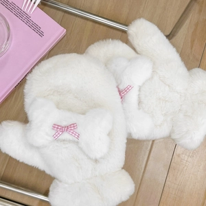 Moffole bianche in peluche con fiocchi scozzesi rosa su un accogliente pavimento in legno