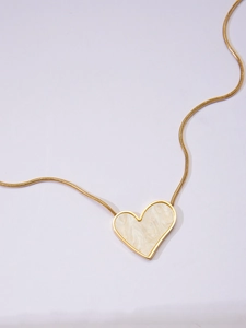 Close-up of heart pendant necklace with gold snake chain and marble texture inlay