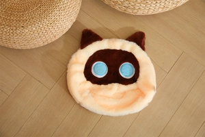 Dettaglio del cuscino di peluche a forma di gatto con pelliccia sintetica e occhi azzurri