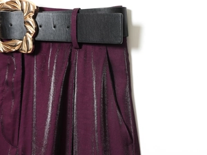 Details von weinroter Faltenhose mit hohem Bund, schwarzem Gürtel und goldener Schnalle