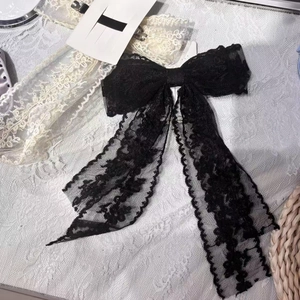 Detailed close-up of a black lace bow hair clip featuring intricate floral embroidery