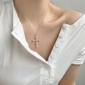 Detail of S925 silver cross necklace with inlaid pearls and stones on collarbone