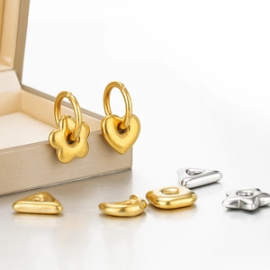 Macro detail of various gold and silver charms including moon, star, and geometric shapes