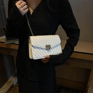 Elegante borsa a tracolla in pelle bianca con trapuntatura a V e fibbia a cuore dorata su modella