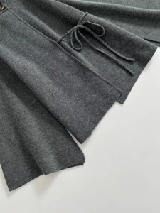 Detail of dark grey knit coat featuring a brown button, drawstring and fine wool texture