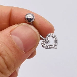 Close-up of a silver stainless steel heart belly ring with sparkling zircons