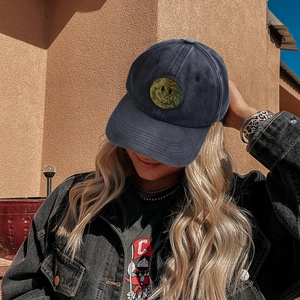 Washed navy cotton baseball cap with sequined smiley face patch in sunny outdoor setting