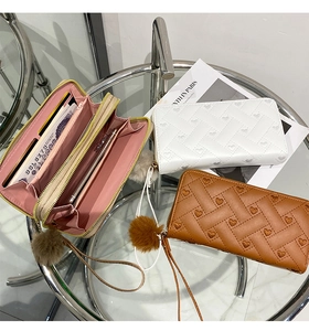 Detail of long woven wallets with heart texture, wristlet, and decorative pom pom
