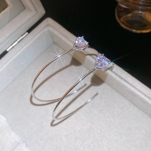 Détail de boucles d'oreilles C en argent avec zircone cœur violet dans une boîte