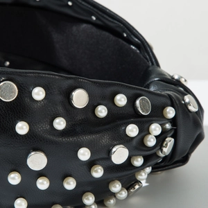 Close-up of black leather headband with inlaid white pearls and silver metal rivets