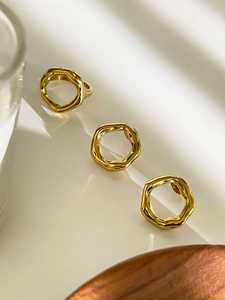Detailed view of three gold irregular wave pattern rings with a textured metallic finish