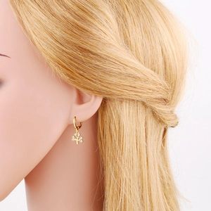 Detail von goldenen Baum-Ohrhängern mit weißen Kristallen, an Model getragen