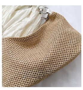 Detail of woven straw texture and silver zipper on a beige summer shoulder bag