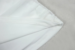 Detail of white mesh fabric layers and fine stitching on a solid color dress