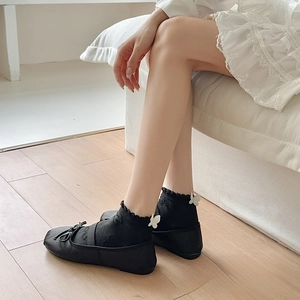 Detail of black JK socks featuring white butterfly bows and ruffled cuffs with flat shoes