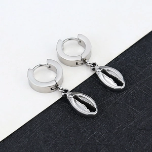 Detailed close-up of silver steel hoop earrings with hanging conch shell charms
