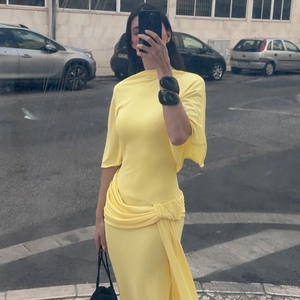 Outdoor mirror selfie showing a yellow backless maxi dress with draped pleat details