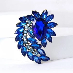 Detailed macro of gold alloy brooch featuring blue crystal waterdrop and navette stones