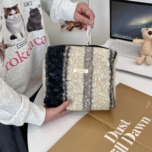 Detailtextuur van gestreepte sherpa fleece toilettas met zachte marine- en beige tinten