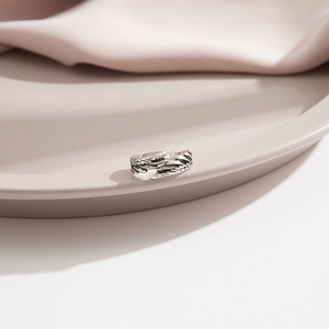 Detailed view of silver feather rings set with adjustable open band on cream silk fabric