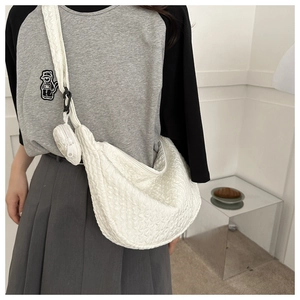Detailed view of a white quilted crescent bag with matching mini round coin purse