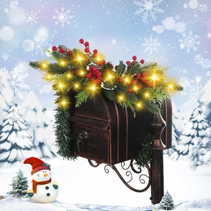 Christmas bronze mailbox with pine needles, berries and warm LED lights in snowy scenery
