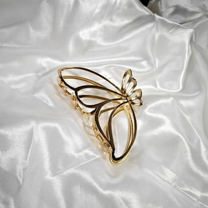 Detailed close-up of golden butterfly hair claw clip with elegant hollow wings design