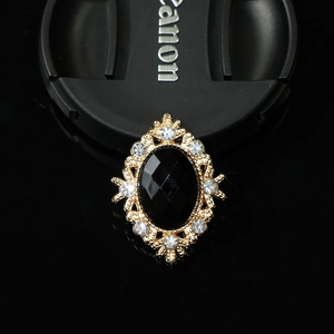 Detailed macro view of vintage gold alloy brooch with black oval gemstone and rhinestones