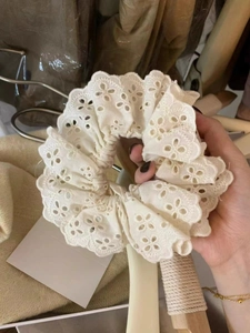 Detailed close-up of white lace scrunchie featuring delicate eyelet embroidery textures