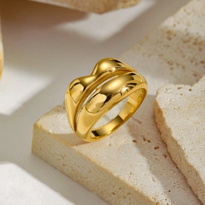 Close-up of golden irregular double-layered wavy ring on a natural stone base