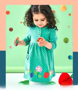 Detail of green long-sleeve girl dress with white polka dots and floral fruit embroidery