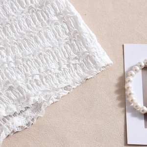 Détail du tissu blanc plissé avec fronces élastiques et accessoire de perles élégant