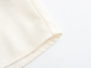 Macro shot of fine ivory chiffon fabric texture and neat hemline stitching detail