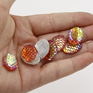 Close-up of golden teardrop resin cabochons with iridescent fish scale texture and flat back