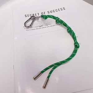 Gros plan d'un porte-clés en nylon tressé vert avec mousqueton argenté sur revue